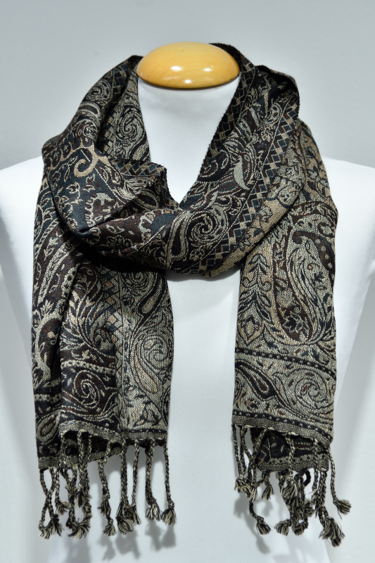 Mörkbrun ullsjal med guldigt paisleymönster och fransar, stylad runt halsen på en vit skyltdocka.
