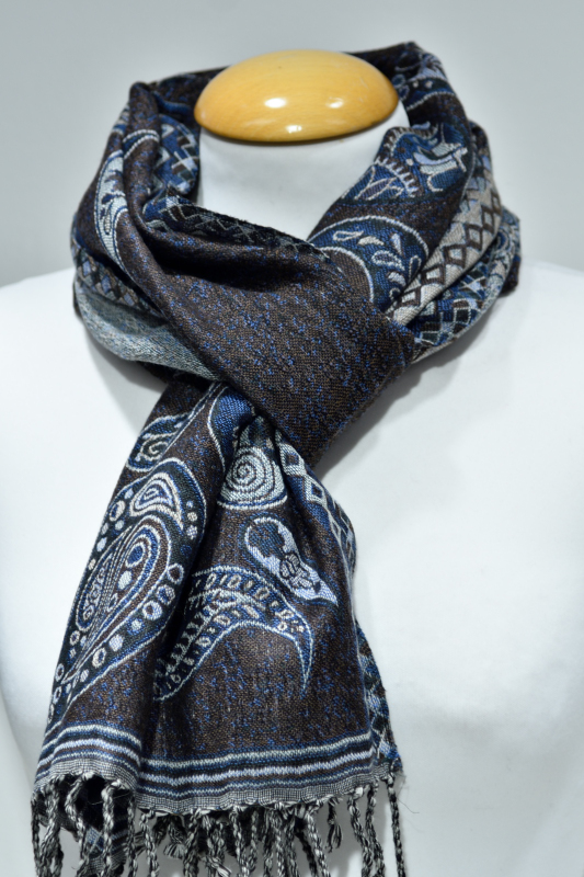Mindre blå ullsjal med paisleymönster och fransar, virad runt halsen på en vit skyltdocka.