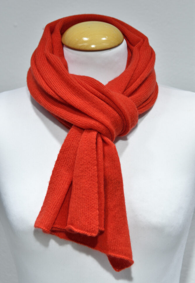 Liten röd halsduk i 100% cashmere knuten runt en skyltdockas hals.