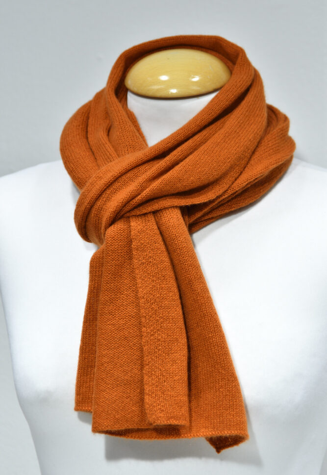 Liten orange halsduk i 100% cashmere knuten runt en skyltdockas hals.