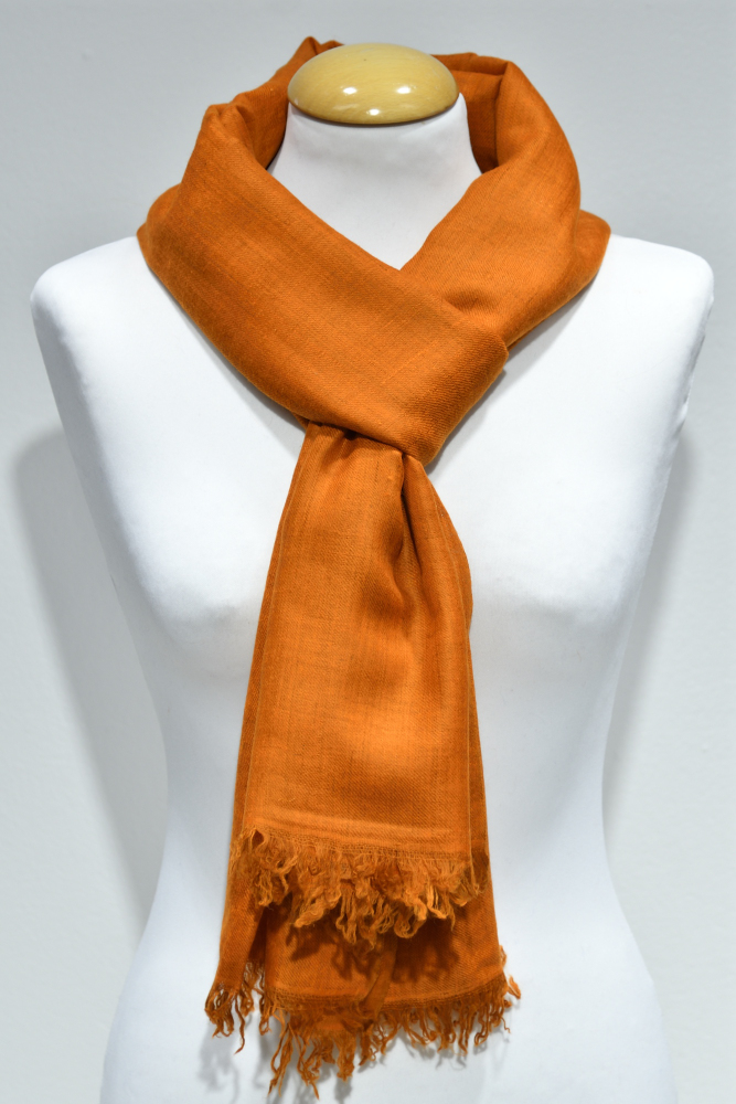 Handvävd pashminasjal i ljus orange på vit provdocka, med fransad kant.
