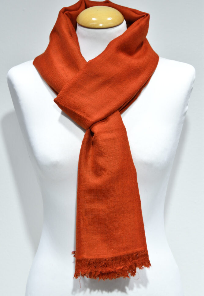 Handvävd pashminasjal i röd-orange på vit provdocka, med fransad kant.