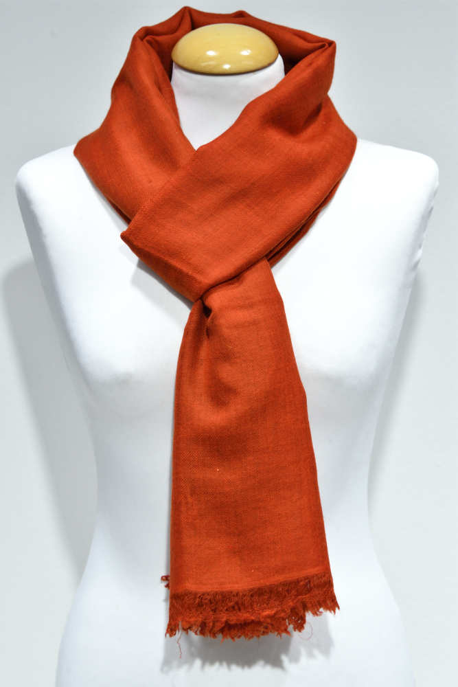 Handvävd pashminasjal i röd-orange på vit provdocka, med fransad kant.