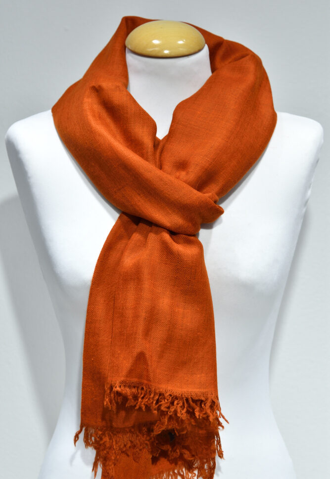 Handvävd pashminasjal i bränd orange på vit provdocka, med fransad kant.